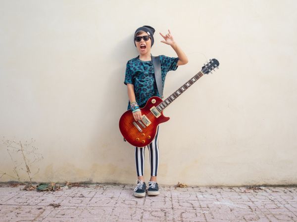 Energetic kid gesturing rock holding guitar