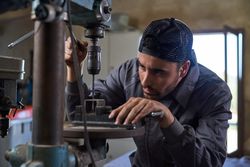Focused master using drilling machine in workshop