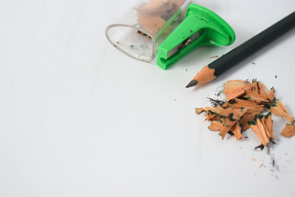 Pencil on table with shavings & green sharpener with space for text