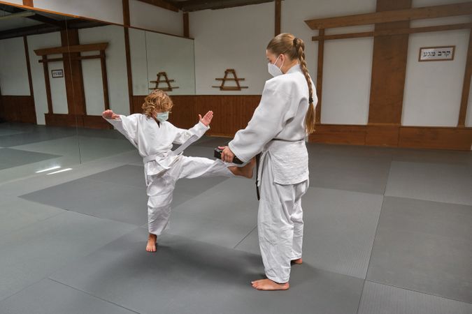Kid in kimono and wearing a mask kicking a mitten that his train