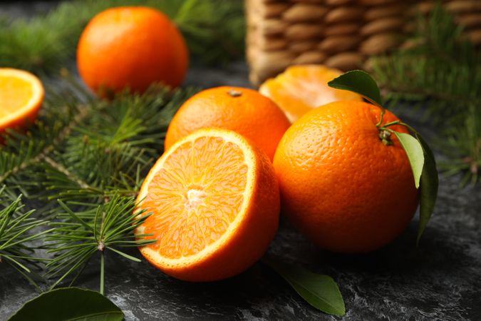Mandarins, pine branches and basket on gray smoky background
