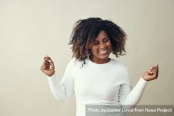 Portrait of happy Black woman with both hands up dancing 5QRm94