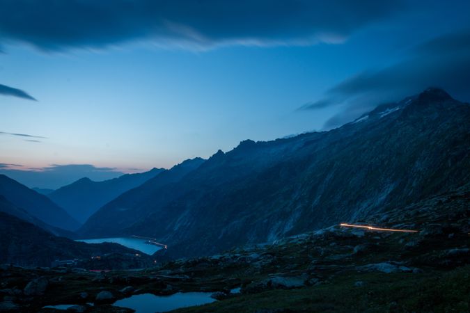 Road and lights over river in mountain valley at dusk