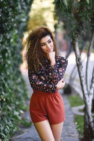 Arab woman wearing casual clothes in the street lined with greenery