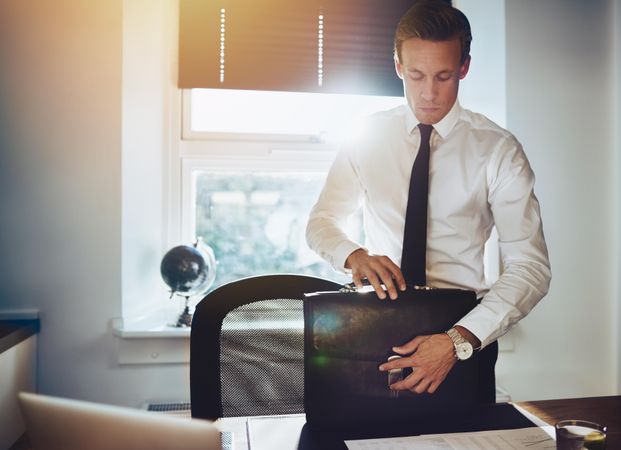 Man in shirt and tie with briefcase in sunny office