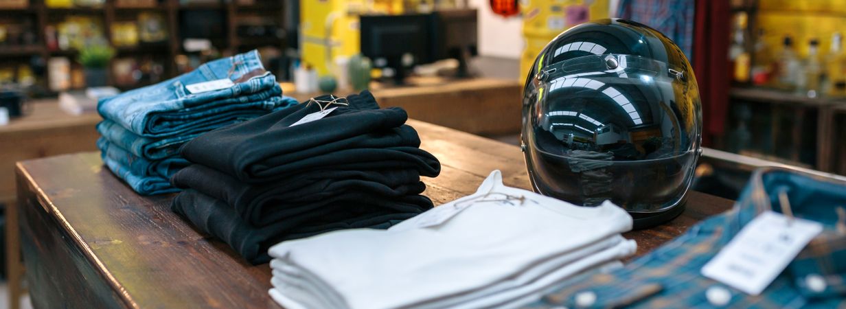 motorbike helmet and new clothes collection over counter on vintage store