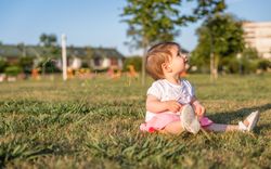 Happy baby girl playing sitting on a grass park