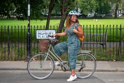 Smiling Black woman stopped with bike next to park
