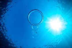 Toroidal bubbles under blue sea water in sunlight