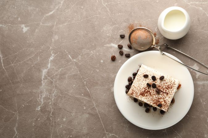 Composition with plate of tiramisu on light brown background. Tasty dessert