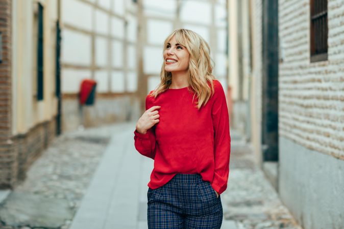 Smiling young blond woman walking down the street
