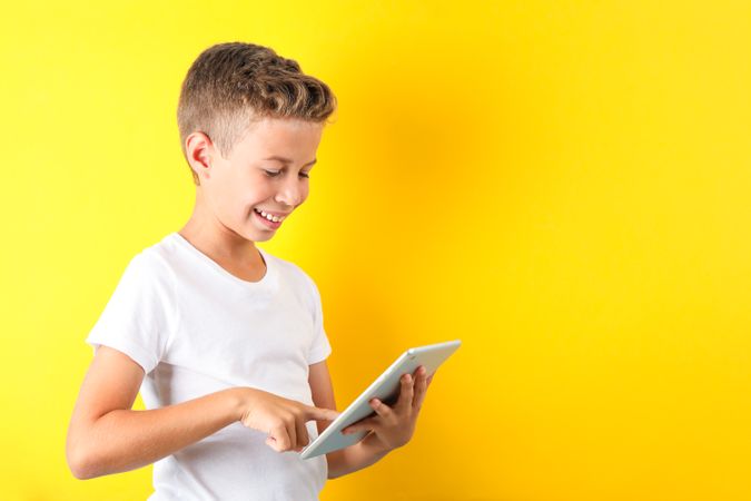 Boy with tablet on color background, space for text