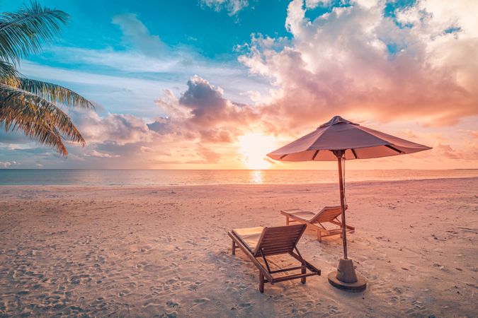 Lounge chairs on the beach with parasol with copy space