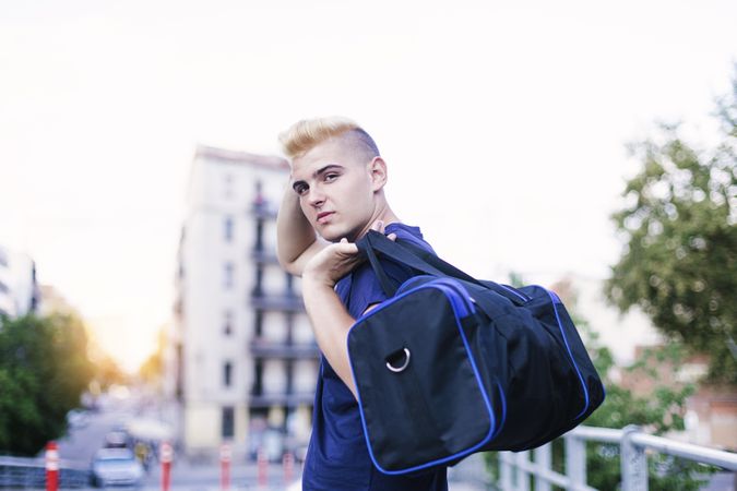 Portrait of young handsome man walking on the street, holding sports bag