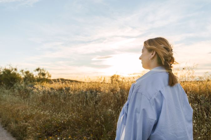 side view of a blonde woman portrait on a field during sunset