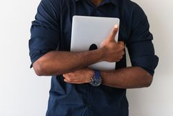 Black guy with laptop near wall