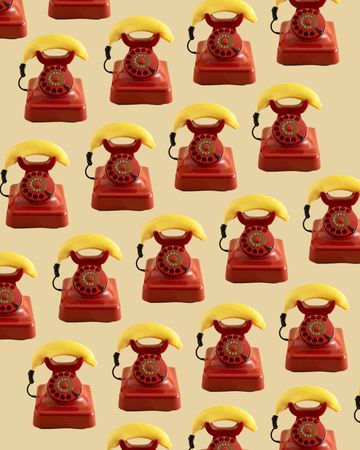 Rows of a vintage red telephone with banana as ear piece