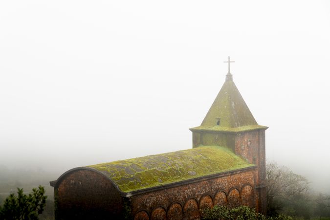 Aged mossy stone chapel in fog