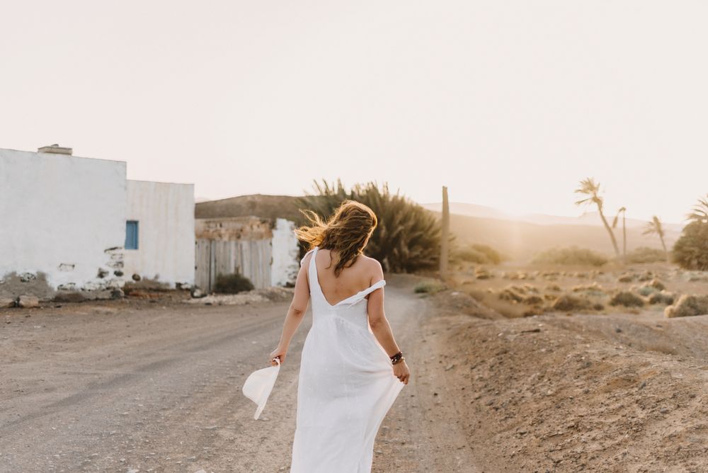 Woman in white dress in dry field in sunlight