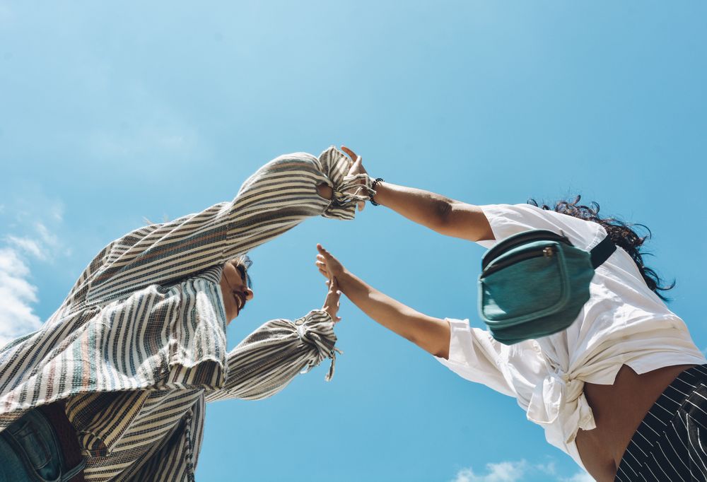 Group of friends embraced and putting their hands together.