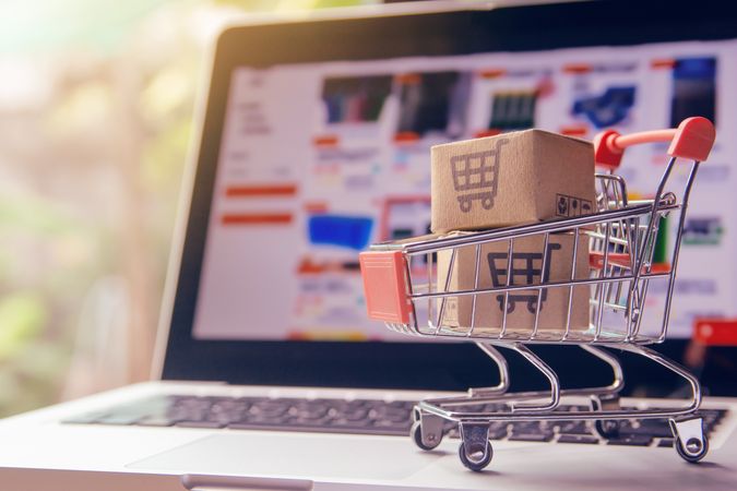 E-Commerce Shopping Concept with Miniature Cart and Boxes on Laptop