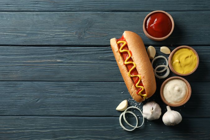Tasty hot dog and ingredients on wooden background