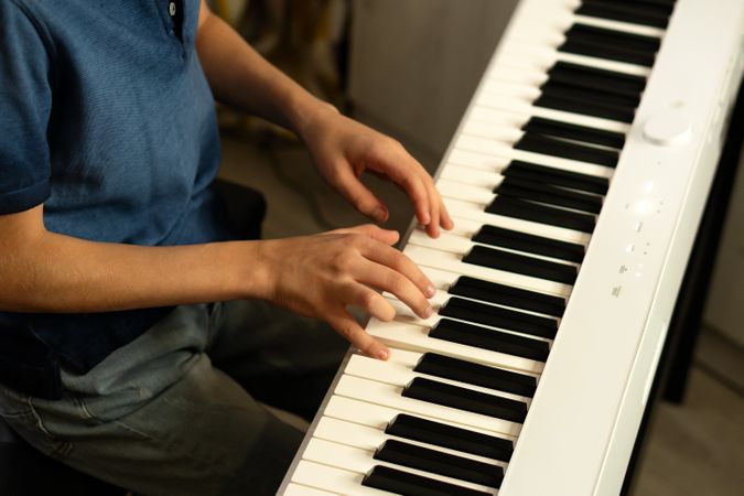 Side view boy's hands skillfully pressing piano keys.