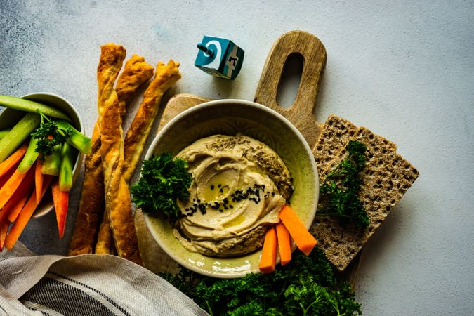 Top view of traditional hummus spread with veggies and crackers to dip