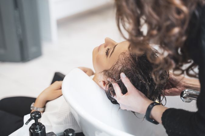 Stylist washing hair of young woman