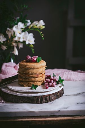 Pile of raspberry pancakes with honey on plate