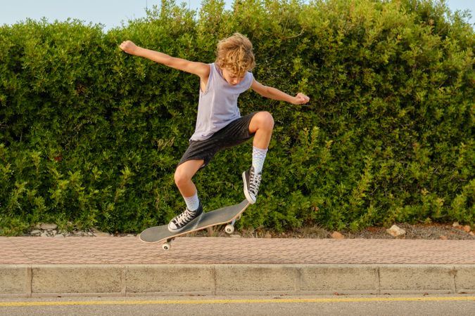 Energetic boy jumping with skateboard in city