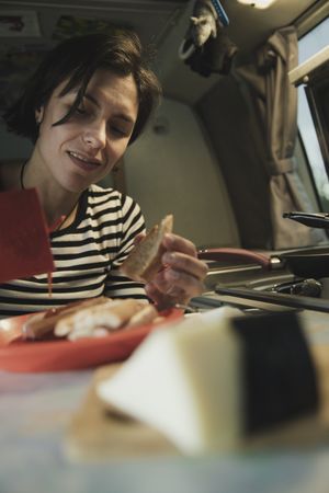 Woman with plate of food near electric cooker in camper van