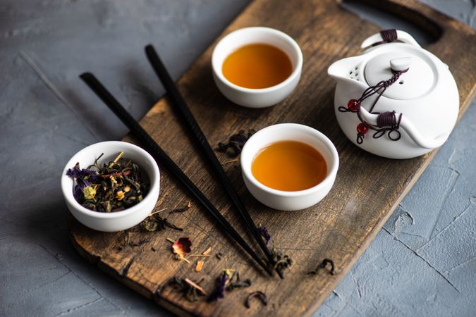 Asian tea time concept of tea pot and loose leaf tea on board