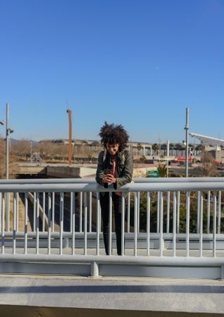 Woman with afro hair looking at her phone while walking.