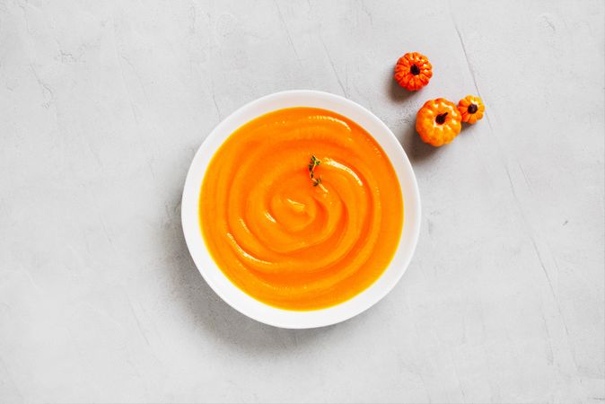 Pumpkin soup on gray background with mini squash, top view