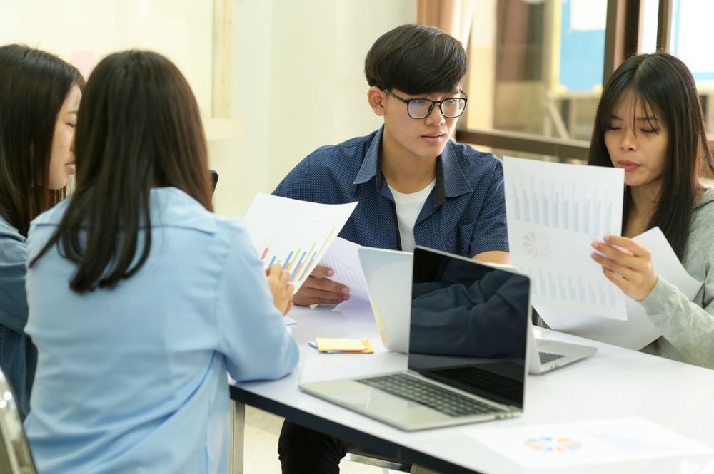 Group of young people brainstorm work with graph and laptop.