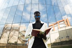 Serious Black businessman reading book in downtown