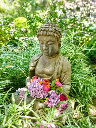 Buddha statue in garden with flowers