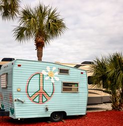 Painted “Hippie” style camper trailer by palm tree e4Bne4