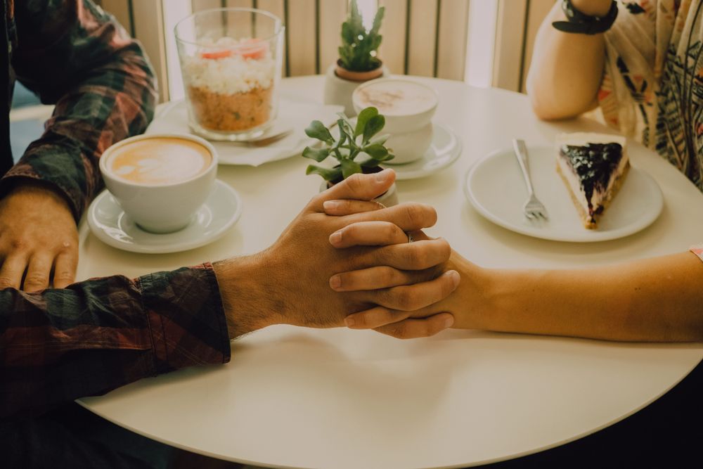 Anonymous loving couple having date in coffee shop
