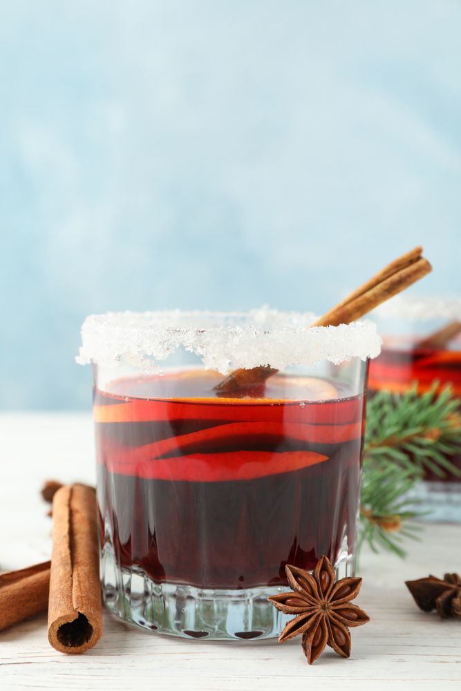 Glasses of tasty mulled wine on blue wooden background, space for text
