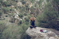 traveling woman sitting on stone in Lotus pose