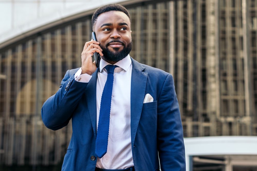 Business Black man in suit talking on the phone while leaving the office