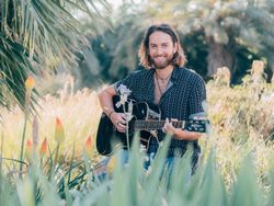 Hipster man in meadow with guitar