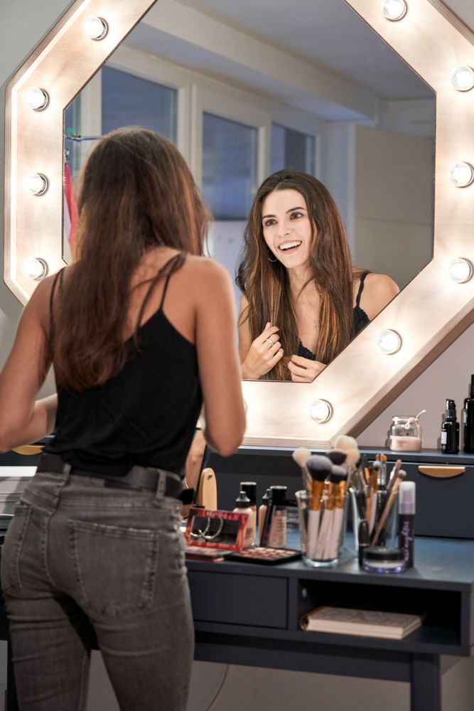 Happy young woman standing near visage table