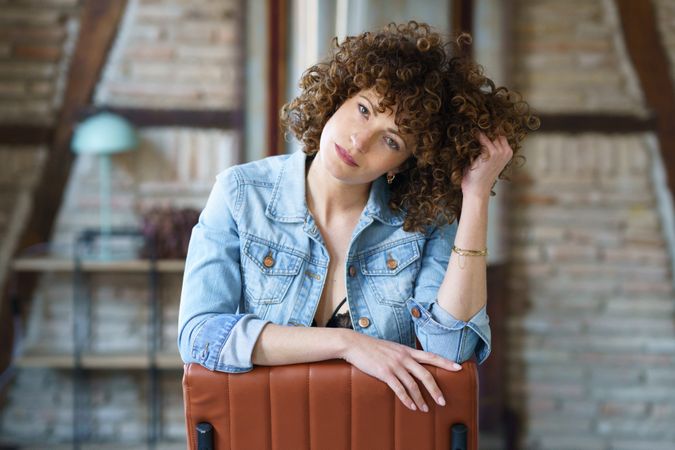 Woman with curly hair sitting on chair reversed playing with her hair