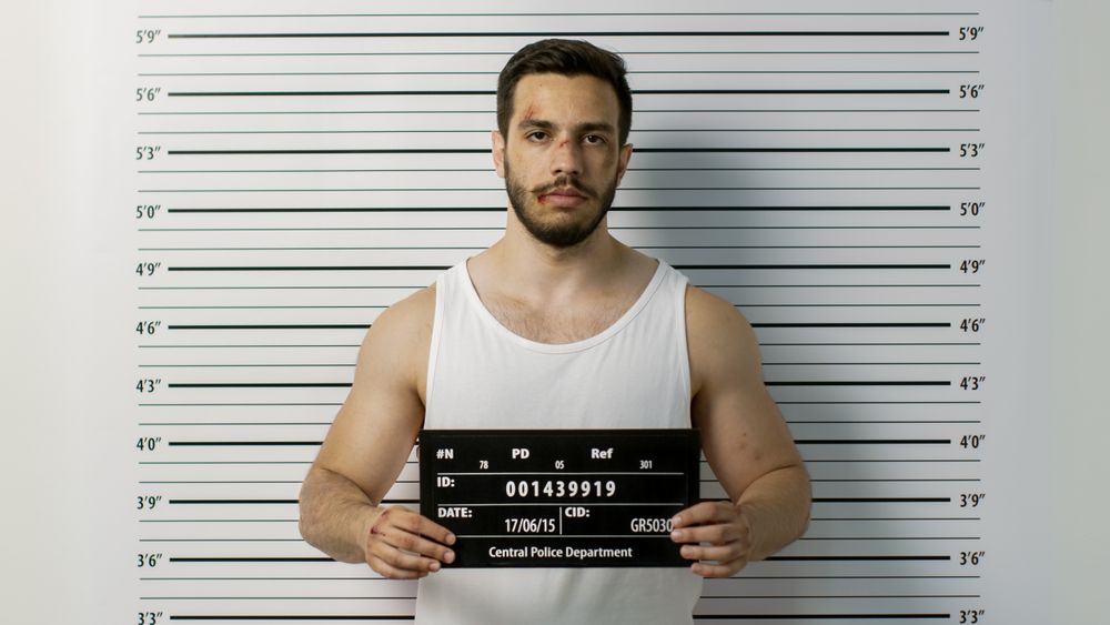 In a Police Station Arrested Beaten Man Poses for Front View Mugshot.