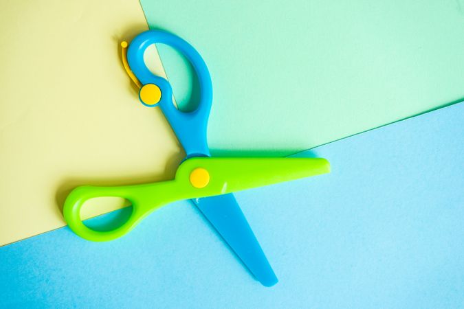 Open blue & green children's scissors on paper background