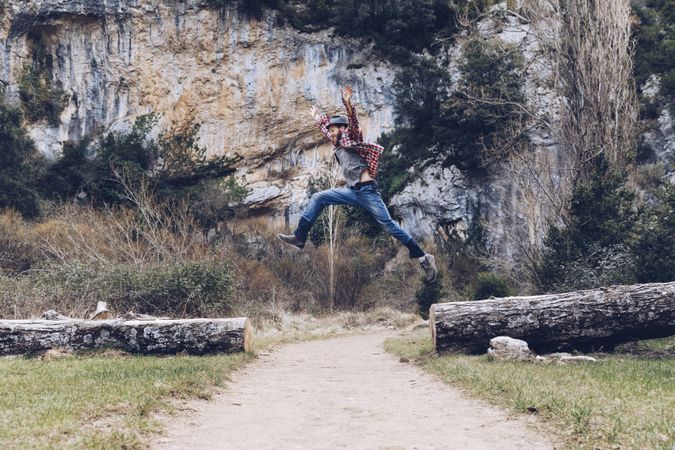 Excited man jumping on trunk in nature