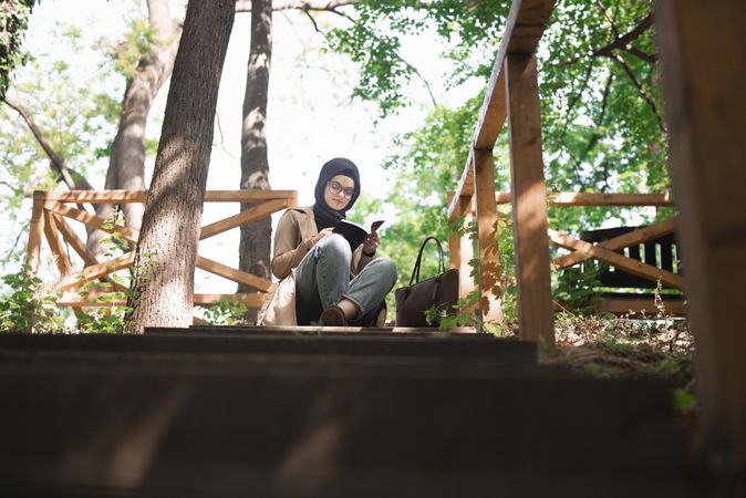 Woman calmly reading in park with trees